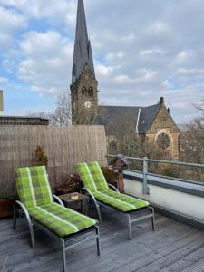zwei Stühle auf einem Balkon mit einer Kirche in der Unterkunft Dachterrassen Idylle über den Dächern Dresdens in Dresden