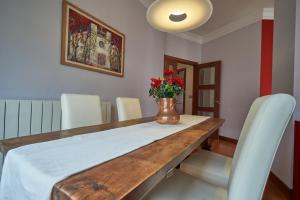 - une table à manger avec des chaises blanches et un vase fleuri dans l'établissement Apartamento BIO Exclusivo con mirador en Bilbao y aparcamiento público gratuito, à Bilbao