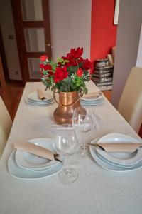 a table with plates and glasses and a vase with red flowers at Apartamento BIO Exclusivo con mirador en Bilbao y aparcamiento público gratuito in Bilbao