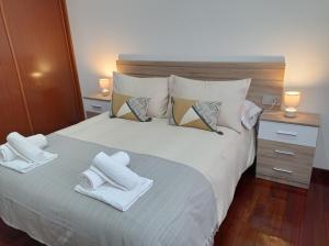 1 dormitorio con 1 cama blanca grande y toallas. en Martínez Padrón Dúplex, en Padrón