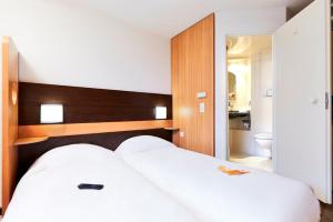 a bedroom with a large white bed and a bathroom at Première Classe Paris-Ouest Gennevilliers in Gennevilliers