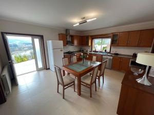 a kitchen with a table and chairs and a refrigerator at Cerdeirinhas de basto Hospedagem in Canedo de Basto