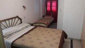 two beds in a room with red curtains at 200 metros peatonal in San Miguel de Tucumán