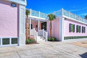 uma casa cor-de-rosa com palmeiras em frente em The Oleander Hotel Room Number 2 em Galveston