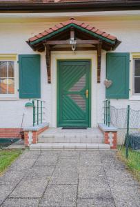 zielone drzwi na białym domu ze schodami w obiekcie Biberland w mieście Kleinkötz