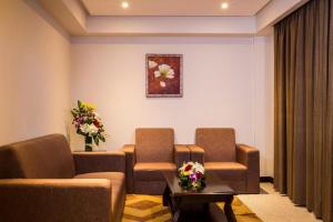 a waiting room with a couch and chairs and flowers at Monroe Hotel & Suites in Manama