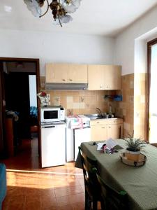 a kitchen with a table and a white refrigerator at One bedroom appartement with balcony and wifi at Monterosso Grana in Levata