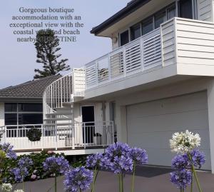 a house with a balcony and purple flowers at Shutters-Waterfront-Private-at Little Blowhole in Kiama