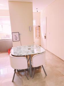 una sala da pranzo con un tavolo e due sedie bianche di LUMIÈRE ALICAR APPTS &SUITES a Buenos Aires