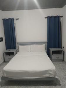 a bedroom with a white bed with blue curtains at RECIDENCIAL MIGNOLI in Boca Chica