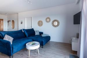 a living room with a blue couch and a table at Apartament Baltic Sea Gate Porta Mare 55m2 in Dziwnówek