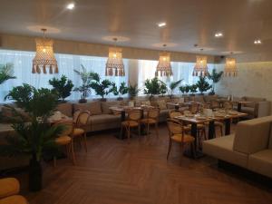 a restaurant with tables and chairs and chandeliers at Ayhan Hotel in Aktobe