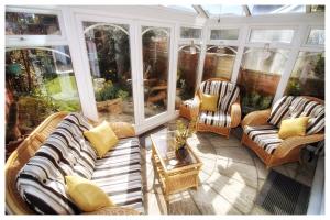 a screened in porch with couches and chairs at Self Contained Flat with Private Garden & Parking in Sandown