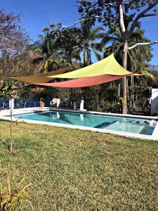 una sombrilla amarilla y roja sobre una piscina en La Leona 1, en El Zonte