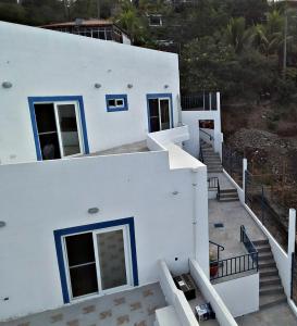 Casa blanca con puertas y escaleras azules en La Leona 1, en El Zonte