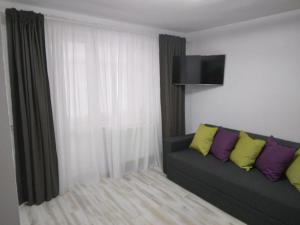 un soggiorno con divano e cuscini gialli e viola di Luxury apartament a Curtea de Argeş