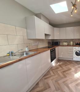 a kitchen with white cabinets and a sink at Kinsale town cosy home 2 min walk to town center in Kinsale
