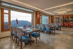 a dining room with tables and chairs and a large window at WelcomHeritage Elysium Resort & Spa in Shimla