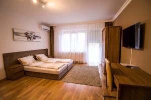 Sala de estar con cama y TV en Thermal Next II Weninger Apartman Kiskunhalas, en Kiskunhalas