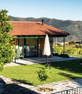 uma casa com um pátio e um guarda-chuva num quintal em Quinta do Monte Travesso - Country Houses & Winery em Tabuaço