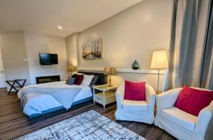 a bedroom with two beds and two chairs and a television at Maple Rise Guesthouse in Duncan