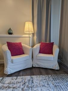 twee witte stoelen met rode kussens in de woonkamer bij Maple Rise Guesthouse in Duncan