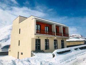 une maison dans la neige devant une montagne dans l'établissement Eltisy Guest House, à Kazbegi