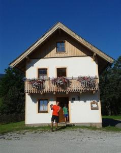 a man standing outside of a house with a balcony at Lechnerhäusl in Maria Alm am Steinernen Meer