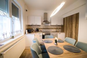 a kitchen and dining room with a wooden table and chairs at Thermal Next I Weninger Apartman Kiskunhalas in Kiskunhalas