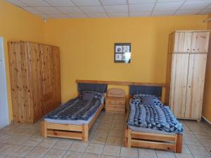 2 camas en una habitación con paredes amarillas y armarios de madera en COLLINGO Belvárosi Szállás, en Kazincbarcika