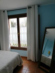 - une chambre dotée d'une fenêtre avec des rideaux blancs et un miroir dans l'établissement capricho 2 asturias COLOMBRES, à Ribadedeva