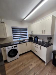 a kitchen with white cabinets and a black counter top at Courtybella Mews in Newport