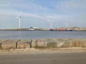dois moinhos de vento e um barco numa massa de água em Strandhytten em Hvide Sande