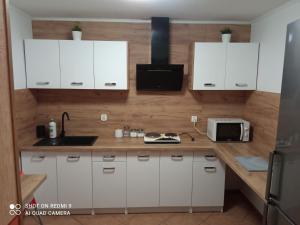 a kitchen with white cabinets and a sink and a microwave at Pokoje Emilia I Julia in Łeba