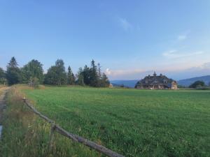 a fence in a field with a house in the background at Wrzosowy Dwór - SPA in Skomielna Czarna