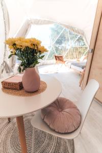 a white table with a vase of yellow flowers on it at Farma Ovčí Terasy in Němčičky