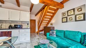 ein Wohnzimmer mit einer grünen Couch und einer Küche in der Unterkunft Karpaczowy Klimat przy Deptaku - 5D Apartamenty in Karpacz