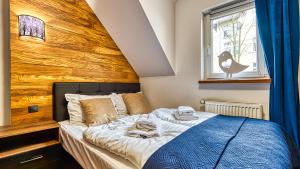 ein Schlafzimmer mit einem Bett mit einer Holzwand in der Unterkunft Karpaczowy Klimat przy Deptaku - 5D Apartamenty in Karpacz