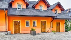 ein orangefarbenes Haus mit einem schwarzen Dach in der Unterkunft Karpaczowy Klimat przy Deptaku - 5D Apartamenty in Karpacz