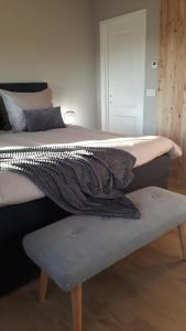 a bedroom with a large bed with a bench under it at B&B Valant in Bruges
