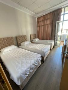 a hotel room with three beds and a window at Hotel Princ in Shkodër