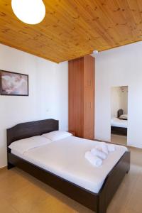 una camera da letto con un letto con lenzuola bianche e un soffitto in legno di Villa Abedini a Ksamil