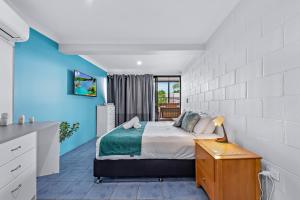 a bedroom with a bed and a blue wall at Airlie Sun & Sand Accommodation Studio #1 in Airlie Beach
