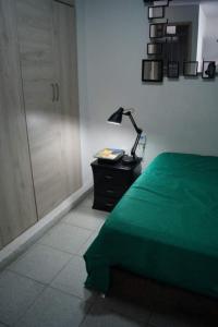 a bedroom with a green bed and a desk with a lamp at VITAL- APARTAMENTO Sector san alonso in Bucaramanga