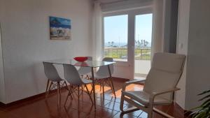 una sala da pranzo con tavolo in vetro e sedie bianche di Carcavelos Surf Beach House a Carcavelos