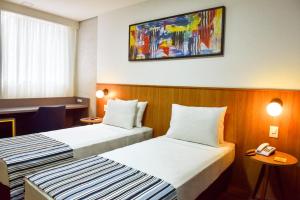 a hotel room with two beds and a phone on the wall at Days Inn By Wyndham Cascavel in Cascavel