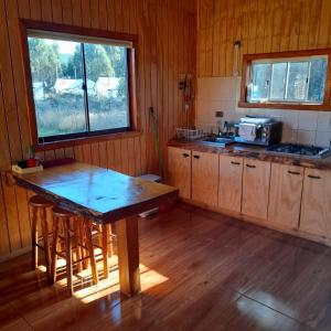 a kitchen with a wooden table and a window at Cabaña Radal C/ Tinaja in Los Lagos +3 photos