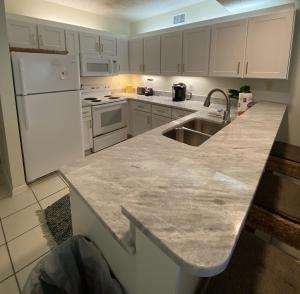 a kitchen with a sink and a white refrigerator at Shoalwater 604 Condo in Orange Beach +26 photos