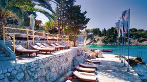 a row of lounge chairs on a wall next to the water at Hotel Podstine in Hvar