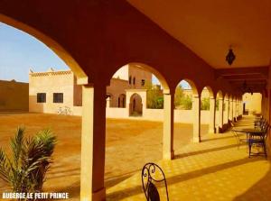 a patio with a table and chairs in a building at Hotel Riad Le Petit Prince in Merzouga